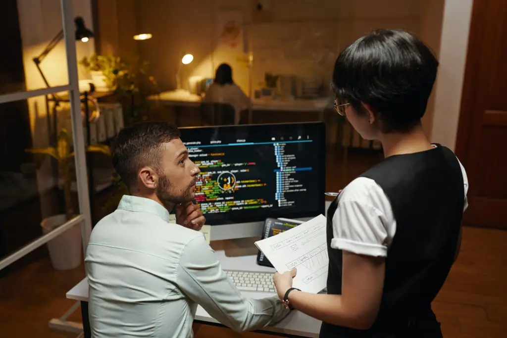 Two ITGuru Canada Inc. colleagues collaborating and discussing code on a computer screen in a