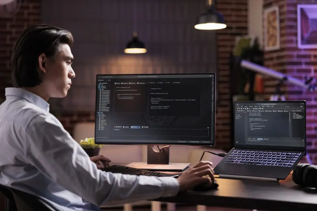 Young man focused on computer code at desk, illustrating website development and technical support services